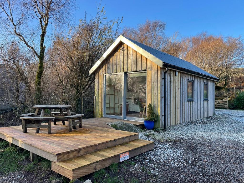 a small wooden cabin with a picnic table and a bench at An Bothan in Isleornsay