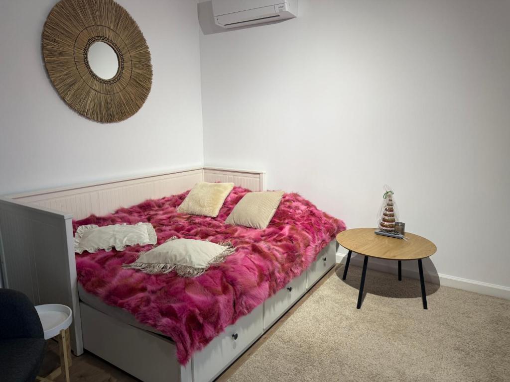 a bedroom with a bed with a pink blanket at Cottage Studio in Borzęcin Duży