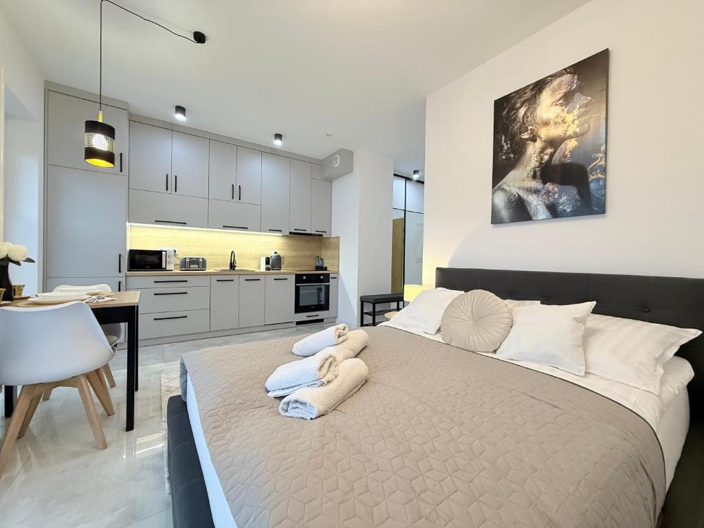 a bedroom with a large bed and a kitchen at Apartament Natura in Piła
