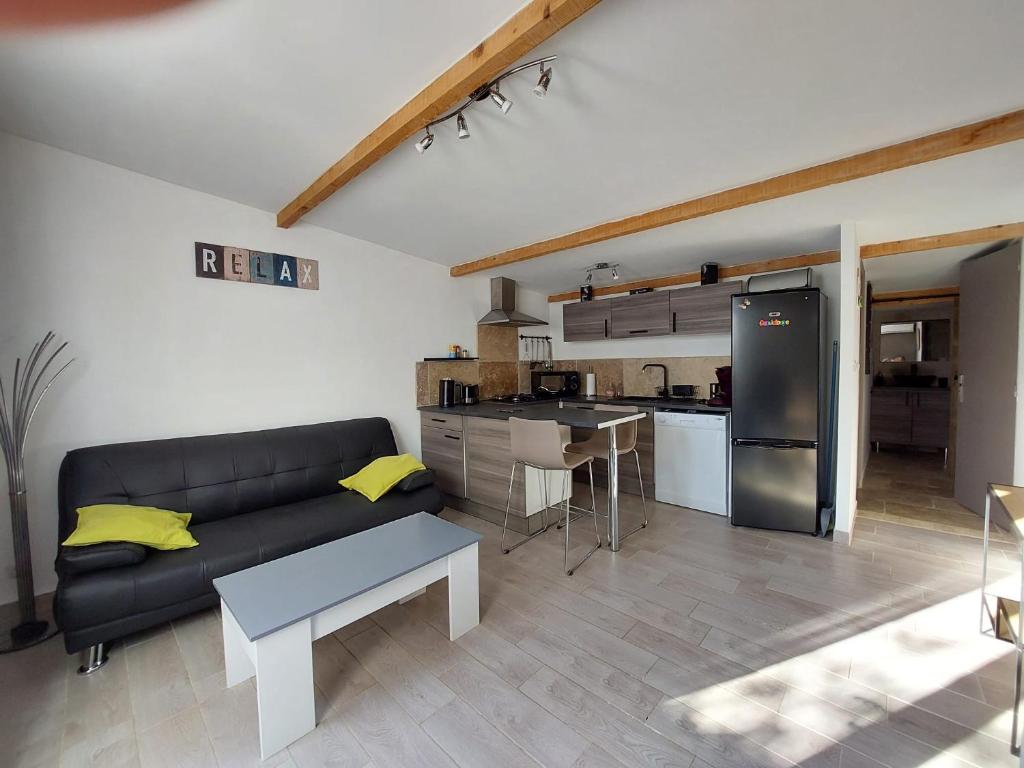 Appartement cosy au cœur de la Provence في جرافيزون: غرفة معيشة مع أريكة سوداء ومطبخ