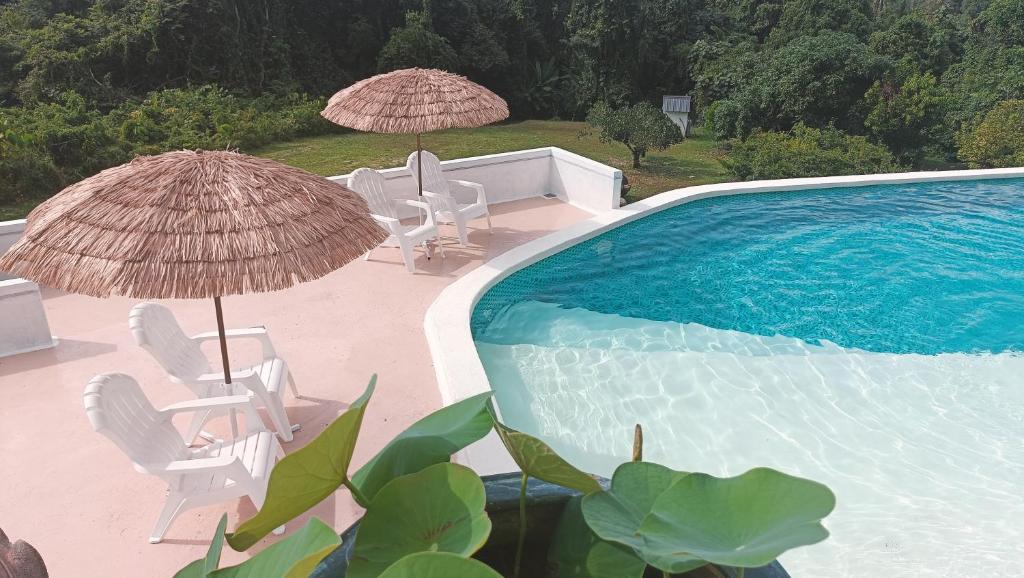 a swimming pool with umbrellas and chairs and a swimming pool at Aza Sunset Villa in Langkawi Intl