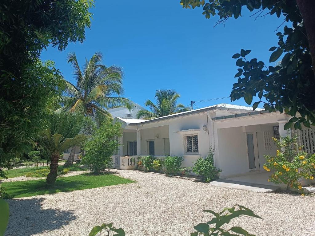 une maison blanche avec des palmiers devant dans l'établissement Les jardins d'Ambondrona, à Mahajanga