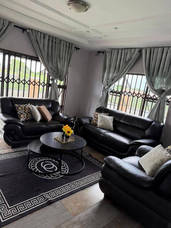a living room with black leather couches and a table at Knovi Guesthouse in Bulawayo