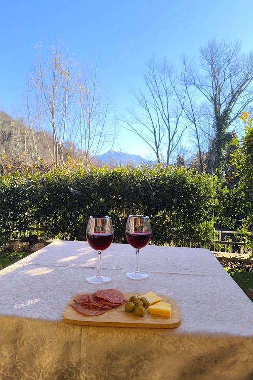 two glasses of red wine and cheese on a table at Appartamento La Ciliegia in Sovere