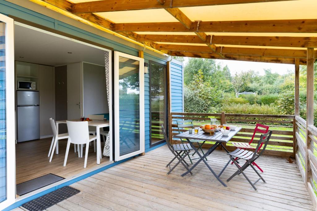 un patio avec une table et des chaises sur une terrasse dans l'établissement Camping Ty Nénez, à Pont-Scorff