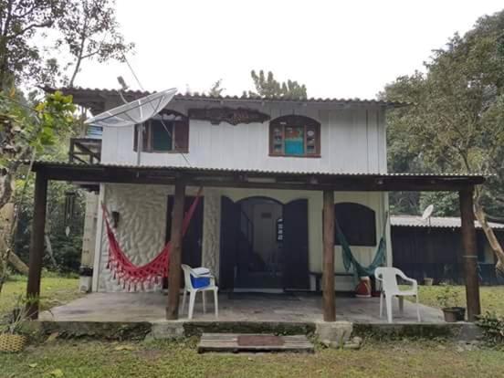 una piccola casa bianca con un portico e due sedie di Recanto da Kaká a Ilha do Mel