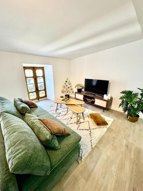 a living room with a green couch and a flat screen tv at L écrin secret de Foix in Foix