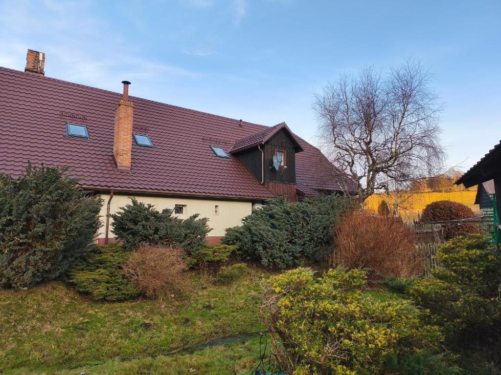 una casa con techo rojo y algunos arbustos en Osmelakowa Dolina, en Spalona