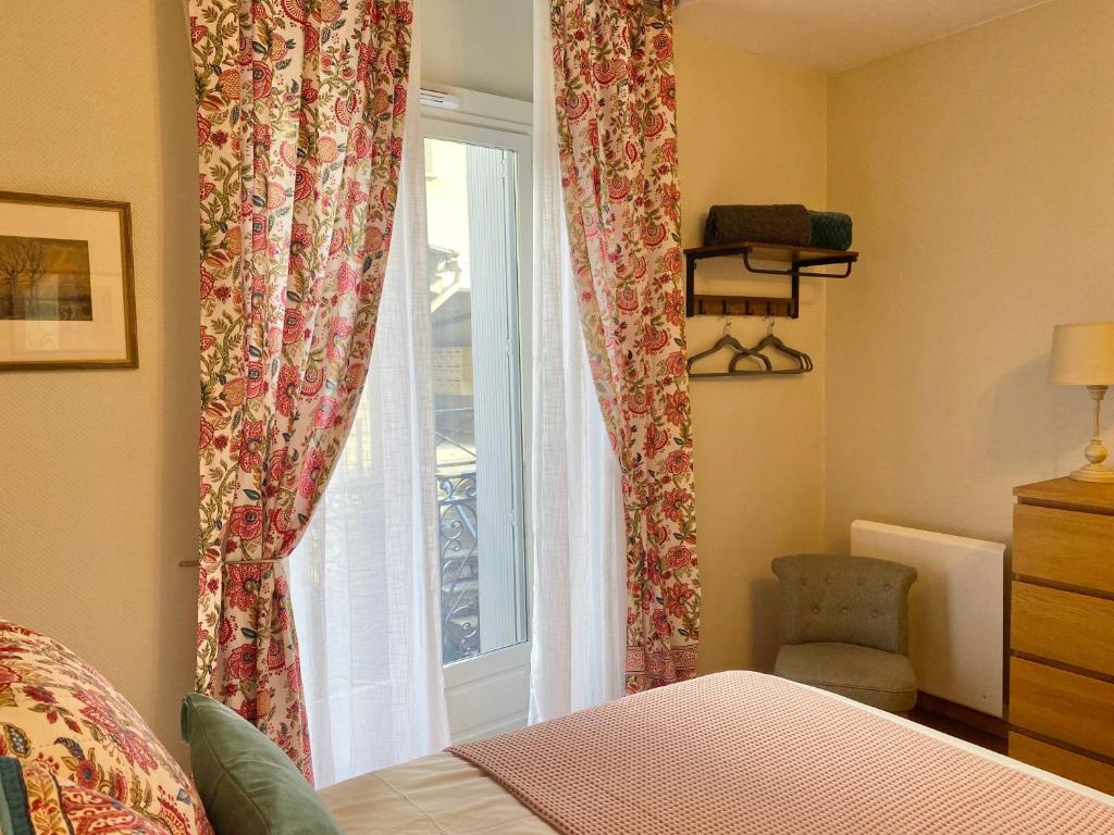 a bedroom with a window with curtains and a chair at Newly Renovated Ground Floor Apartment close to Thermes in Luchon