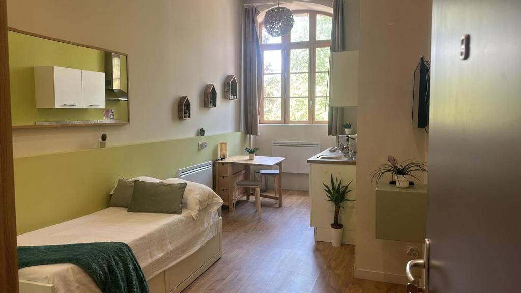 een kleine kamer met een bed en een bureau. bij Dina chic calme cosy in Saint Etienne