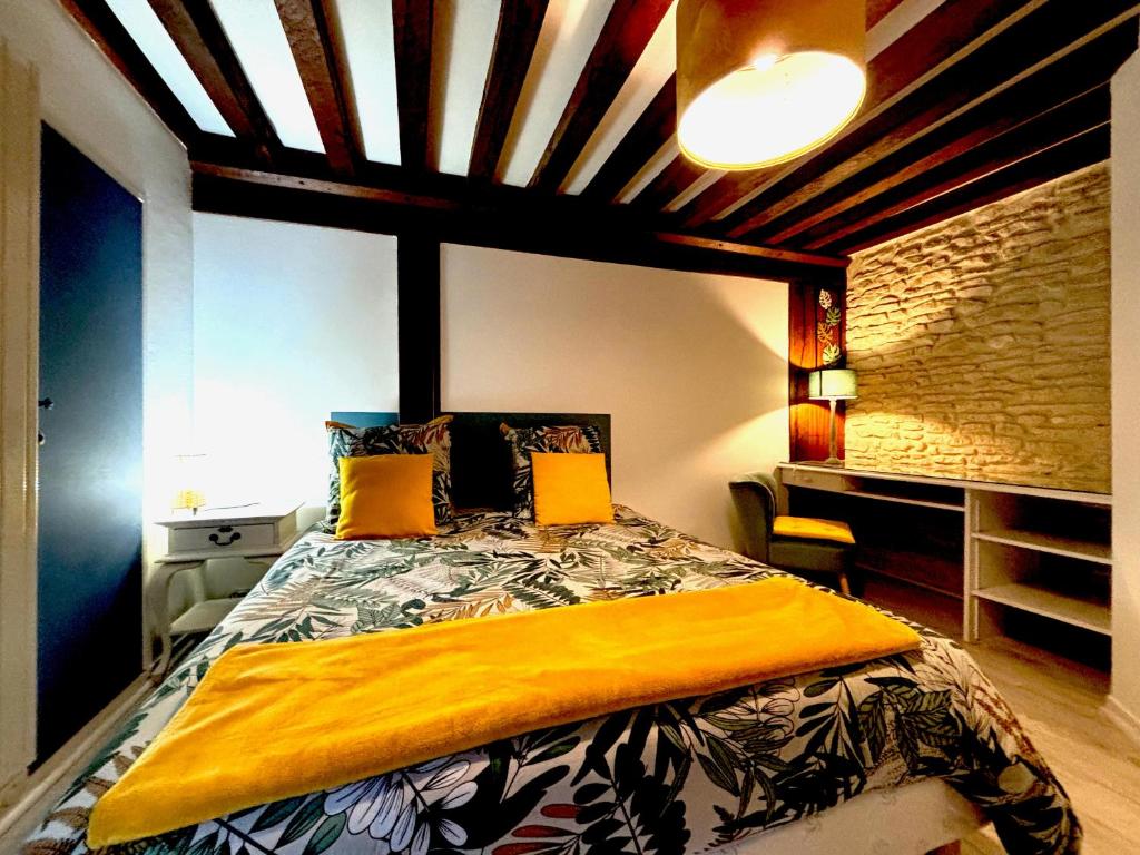 Un dormitorio con una cama con una manta amarilla encima. en Cosy Zénith, en Caen