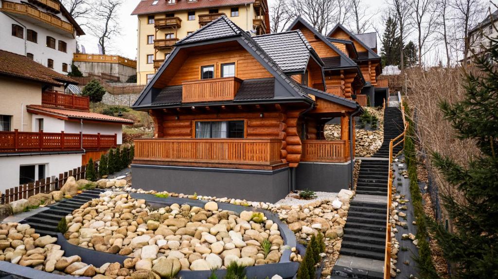 a log house with a rock garden in front of it at Nebbia Ressort in Karpacz
