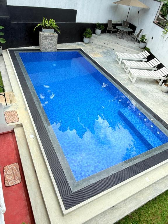 a large swimming pool with blue water in a yard at Pineapple Surf Villa in Ahangama