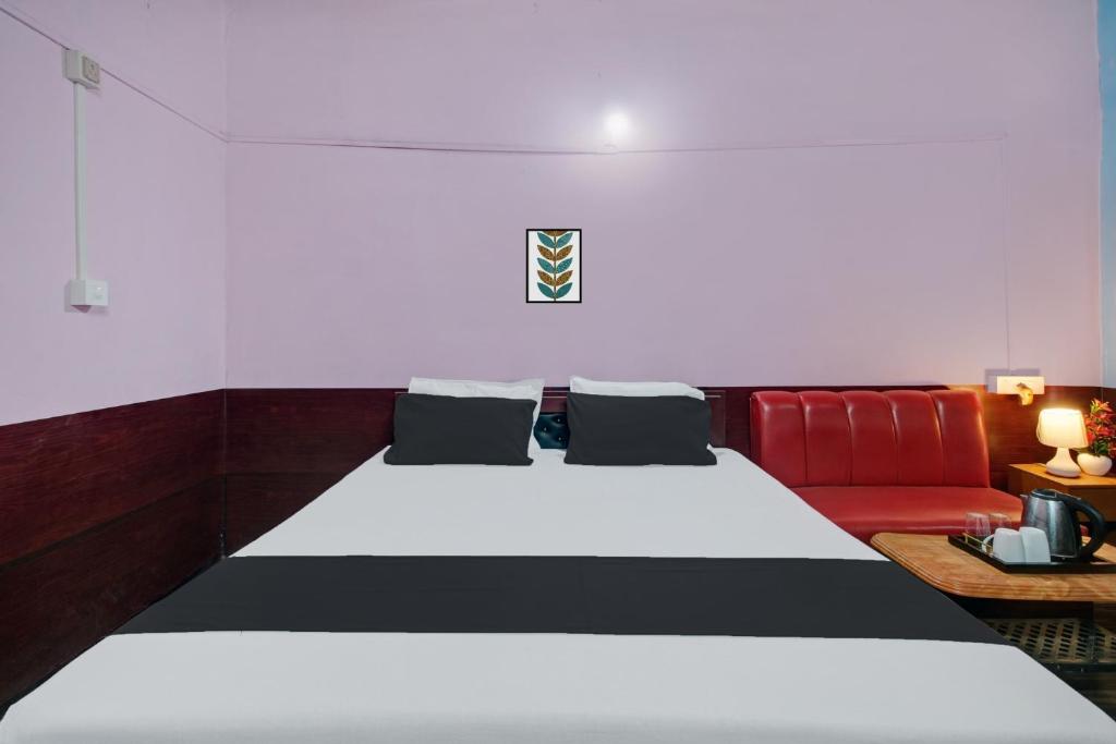 a bedroom with a bed and a red couch at Hotel O Heritage Nest Resort Kazirnga in Kāziranga