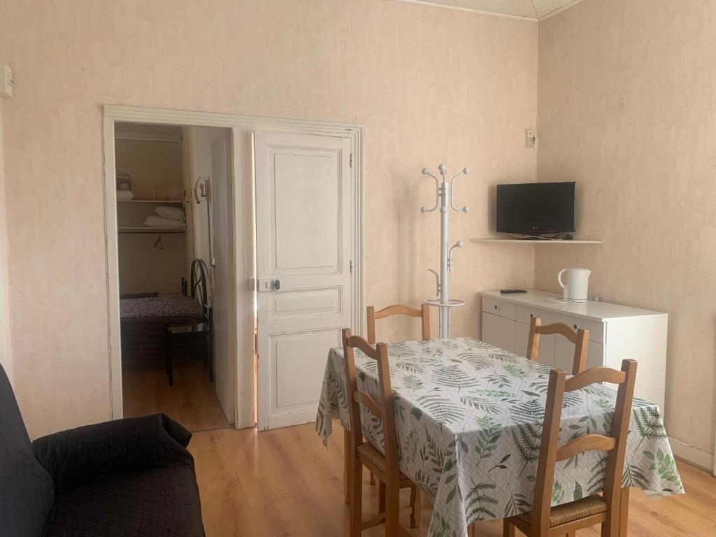 a dining room with a table and chairs and a television at Villa Ramuntcho in La Bourboule