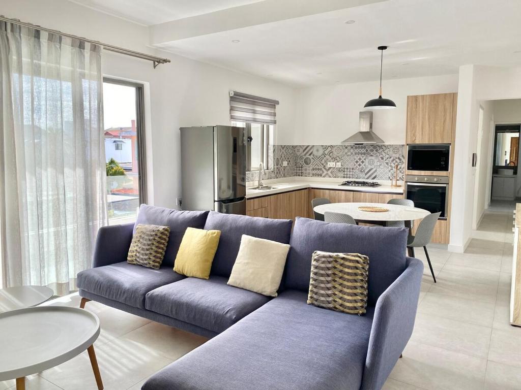 Una sala de estar con un sofá azul y una cocina. en Tempus Central - Bazaar Metro Supermarket Resto, en Quatre Bornes