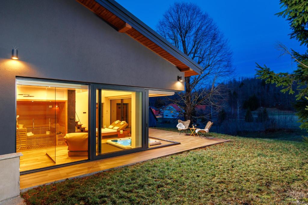 a house with glass doors on a deck at Valdora Forest Oasis - Spa Villa Fužine in Fužine