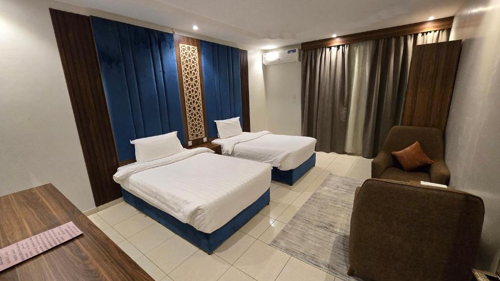 a hotel room with two beds and a chair at ابراج التاج للشق المخدومة جدة in Jeddah