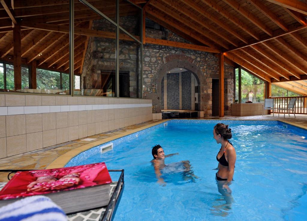a woman and a child in a swimming pool at Hotel La Sapinière in Brioude