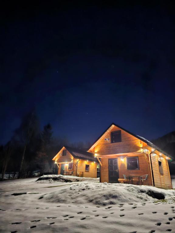 a house with lights on in the snow at night at Domki Mosorczyk in Zawoja