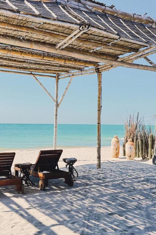 a beach with two lounge chairs and the ocean at Ipuana Virgin Beach in Manaure