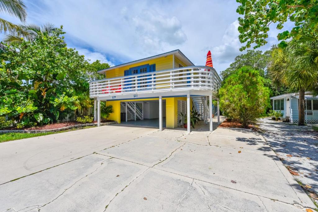 a yellow house with a white balcony and trees at Banana Cabana by Beachside Management in Siesta Key