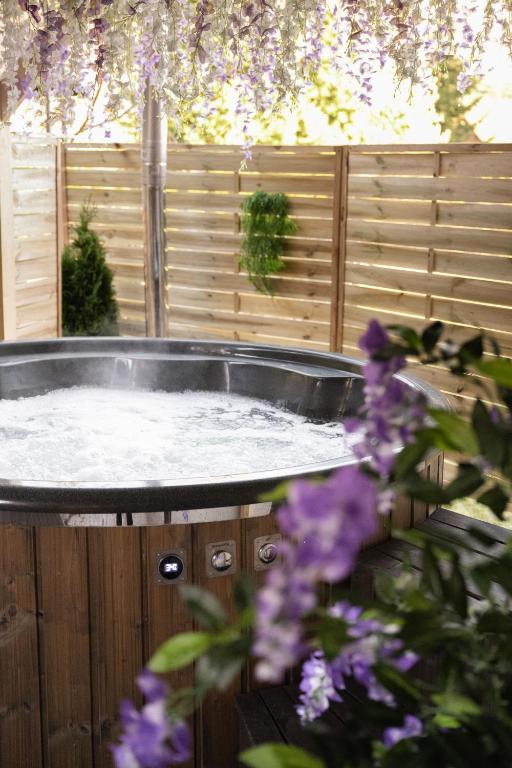a hot tub in a garden with purple flowers at Kominkowy Chill - Jacuzzi, Sauny & Wybrane apartamenty z prywatnym jacuzzi in Zakopane