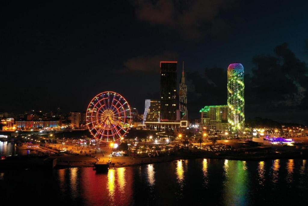 a city skyline at night with a ferris wheel at PANORAMA In Orbi complex central Hotel in Batumi