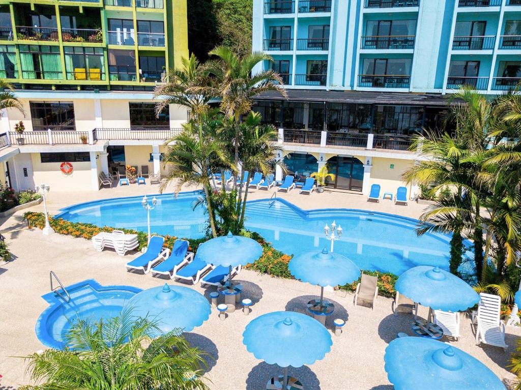 Una piscina con sombrillas y sillas azules y un edificio. en Penthouse con vistas espectaculares del Lago de Atitlán, en Panajachel