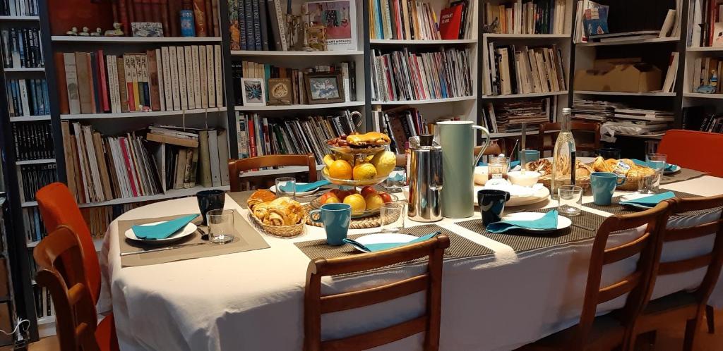 Una mesa en una biblioteca con un mantel blanco y comida. en La Musicale, en Rouen