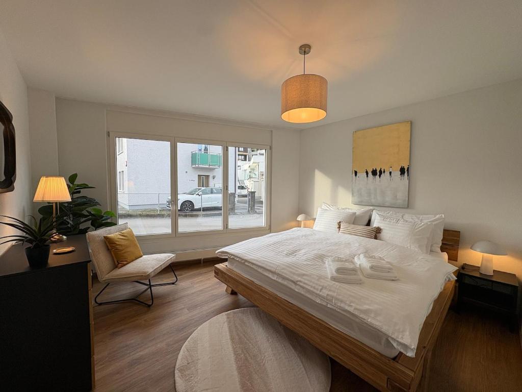 a bedroom with a large white bed and a chair at Alpine Loft in Interlaken