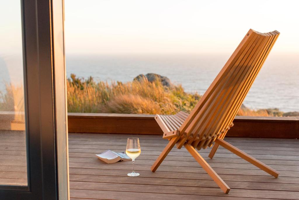 a glass of wine and two chairs on a deck at Timber Cove Resort in Jenner