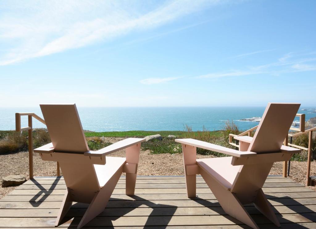 two chairs on a deck with the ocean in the background at Timber Cove Resort in Jenner