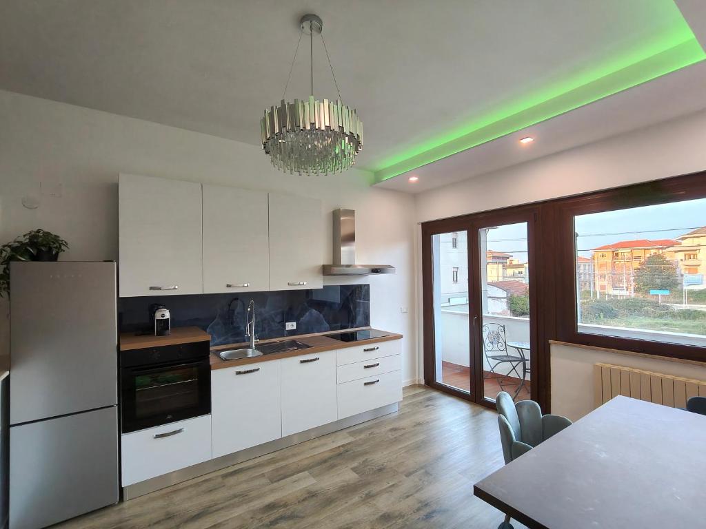 une cuisine avec des placards blancs, une table et un lustre dans l'établissement Suite il Sogno, à Francavilla al Mare