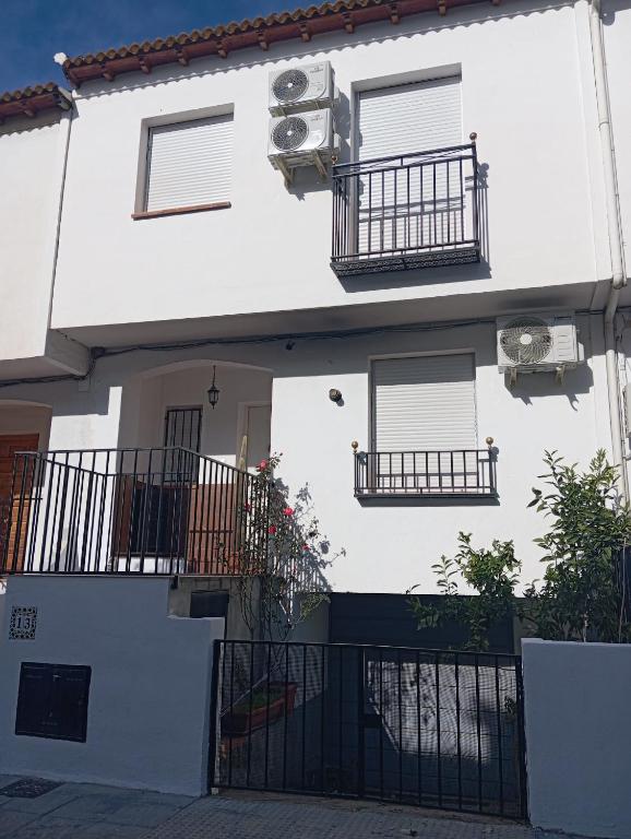 a white house with two balconies and a gate at Casa de la Fortuna in Huétor Vega
