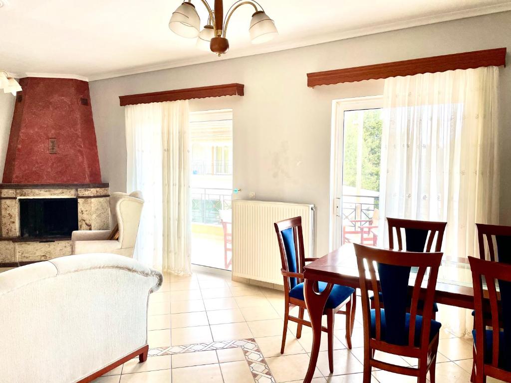Una sala de estar con mesa y sillas y una chimenea. en Casa Verde Blu, en Perivólion