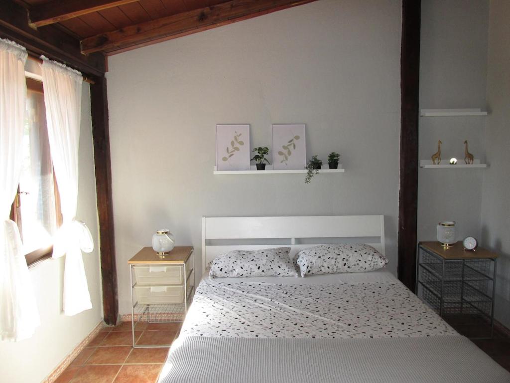 Un dormitorio con una cama blanca y dos mesitas de noche. en Private house with car park at nemi lake, 