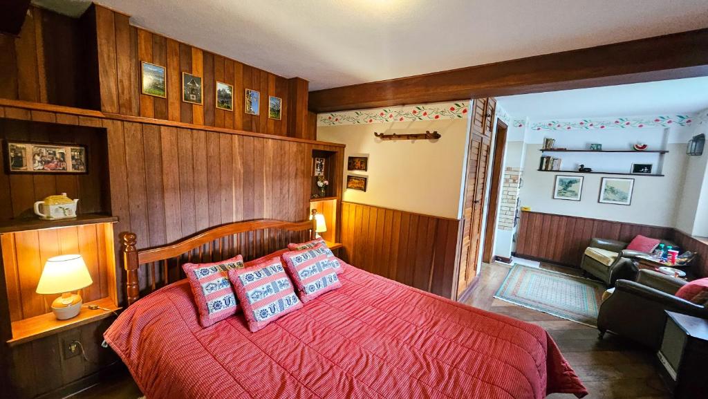 een slaapkamer met een bed met rode dekens en kussens bij Estalagem Entardecer da Serra in Monte Verde