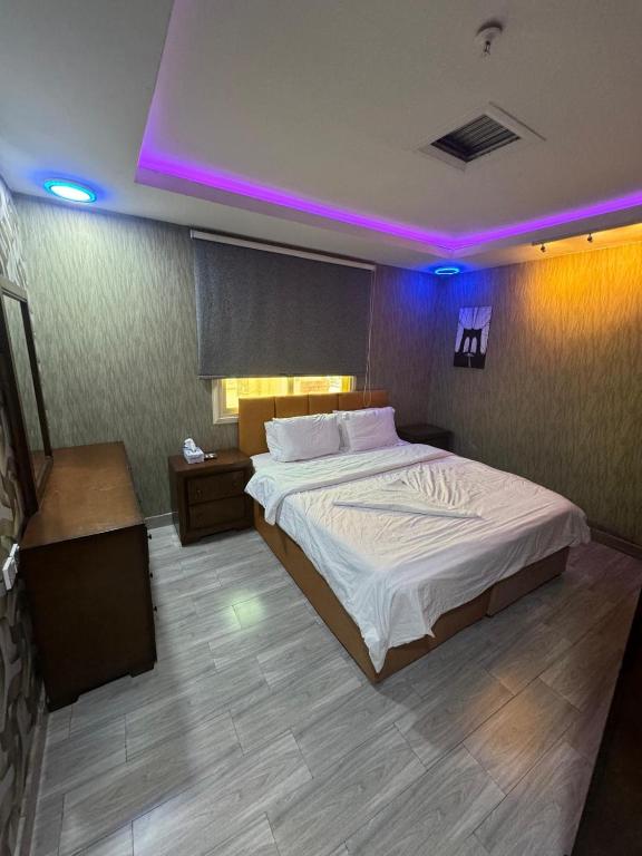 1 dormitorio con 1 cama grande con luces moradas en ماي سويت, en Kuwait