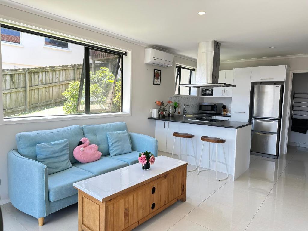 a living room with a blue couch and a kitchen at Albany Sunny Deck Retreat in Auckland