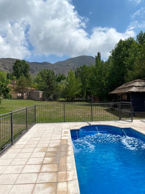 ein Schwimmbad mit einem Zaun und Bergen im Hintergrund in der Unterkunft Cabañas Las Carditas in Mendoza