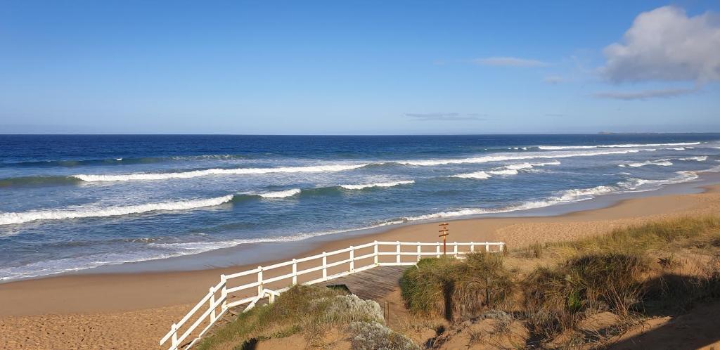 a white fence on a beach next to the ocean at Kipsie Cottage - Point Lonsdale in Point Lonsdale