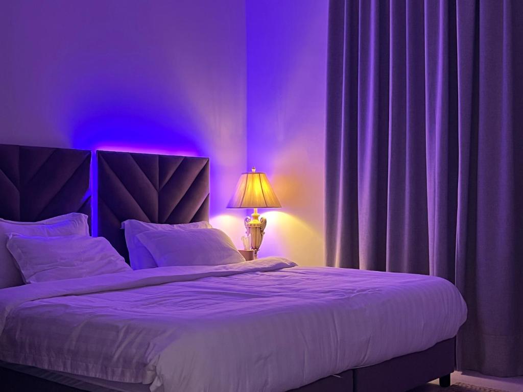 ein lila Schlafzimmer mit einem Bett und einer Lampe in der Unterkunft شقة خاصة in Dschidda