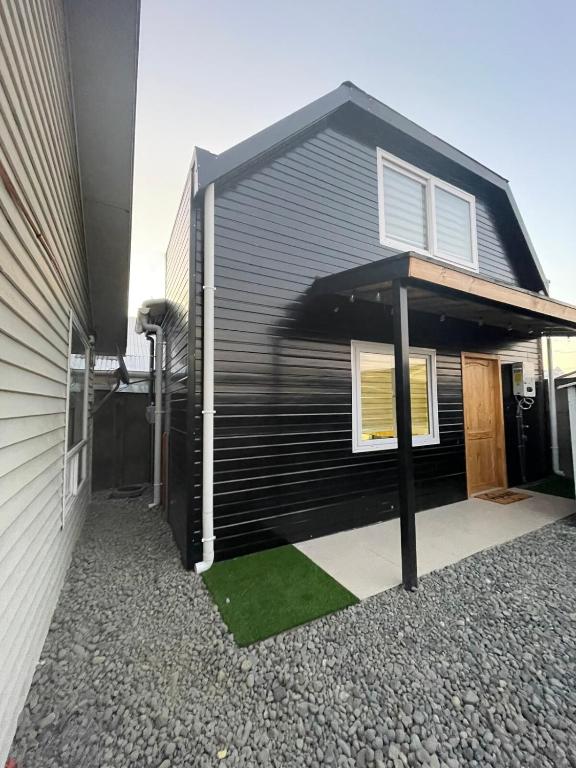 a black house with a green lawn in front of it at Departamento interior in Puerto Montt