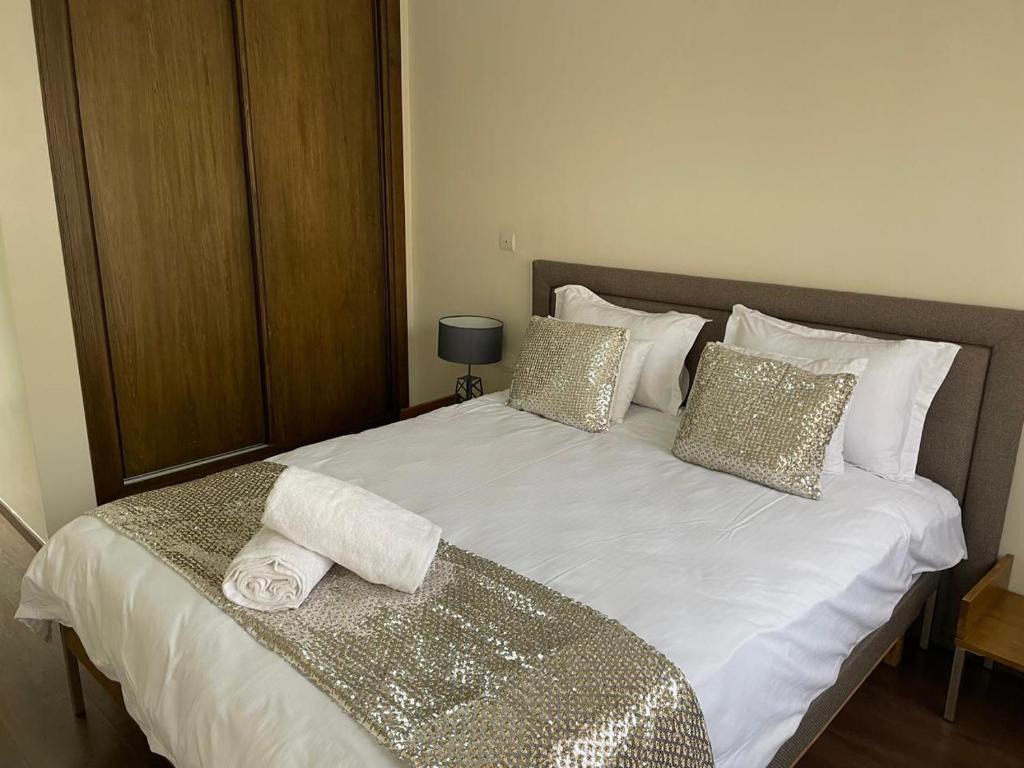 Una gran cama blanca con almohadas doradas y blancas. en Magnifique Appartement familial avec piscine, en Mohammedia