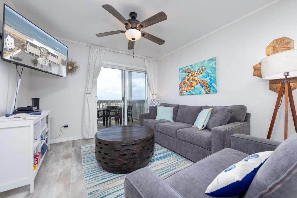 a living room with a couch and a ceiling fan at Beachfront Condo with Ocean Views and Pool Access in Croatan Shores