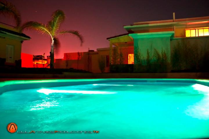 a swimming pool with blue lights in front of a house at Hotel Esmeralda in Piriápolis