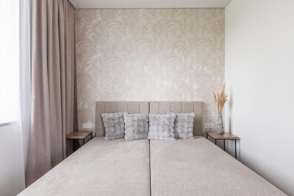 een witte slaapkamer met een groot bed met kussens bij Varenastay in Varėna