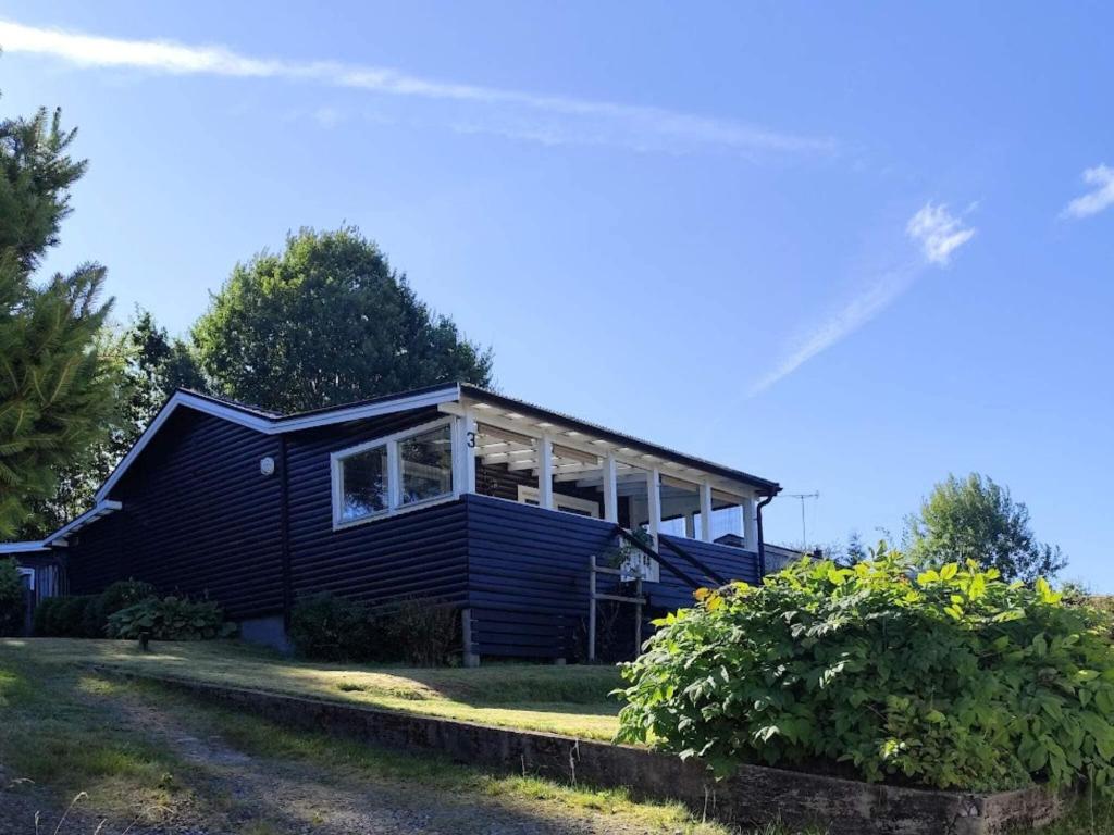 una casa azul con porche en el césped en 4 star holiday home in BORÅS, en Borås