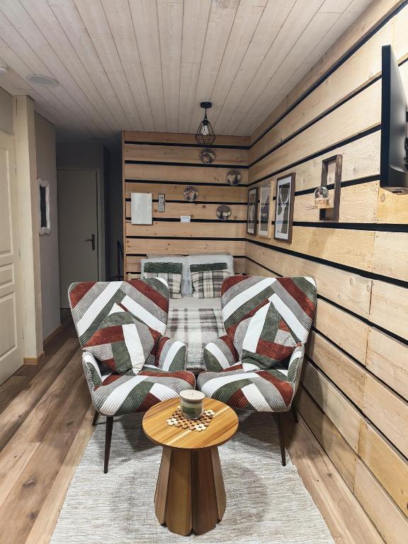 ein Wohnzimmer mit zwei Stühlen und einem Tisch in der Unterkunft Studio Stylisé Chalet in Rochejean